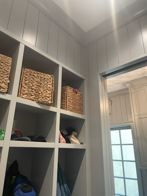 Gray custom mudroom cabinetry with open cubbies, woven baskets, and tall upper storage