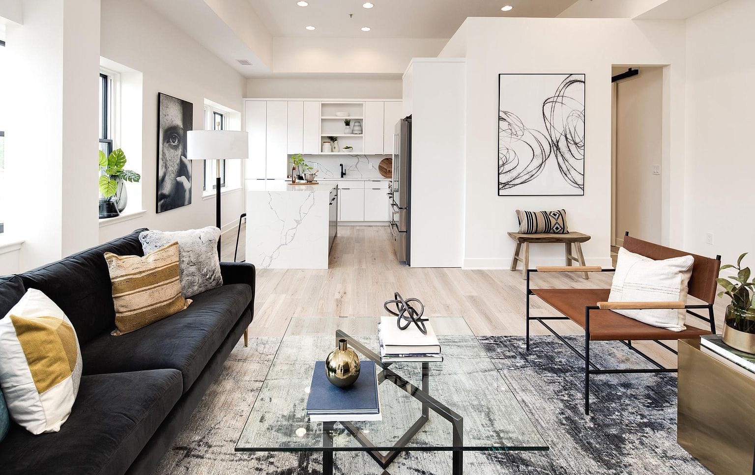 Open-plan living space looking toward a modern white kitchen with integrated cabinetry